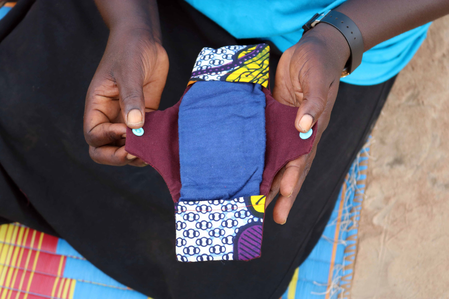 An LWF case worker shows a student how to sew reusable pads.