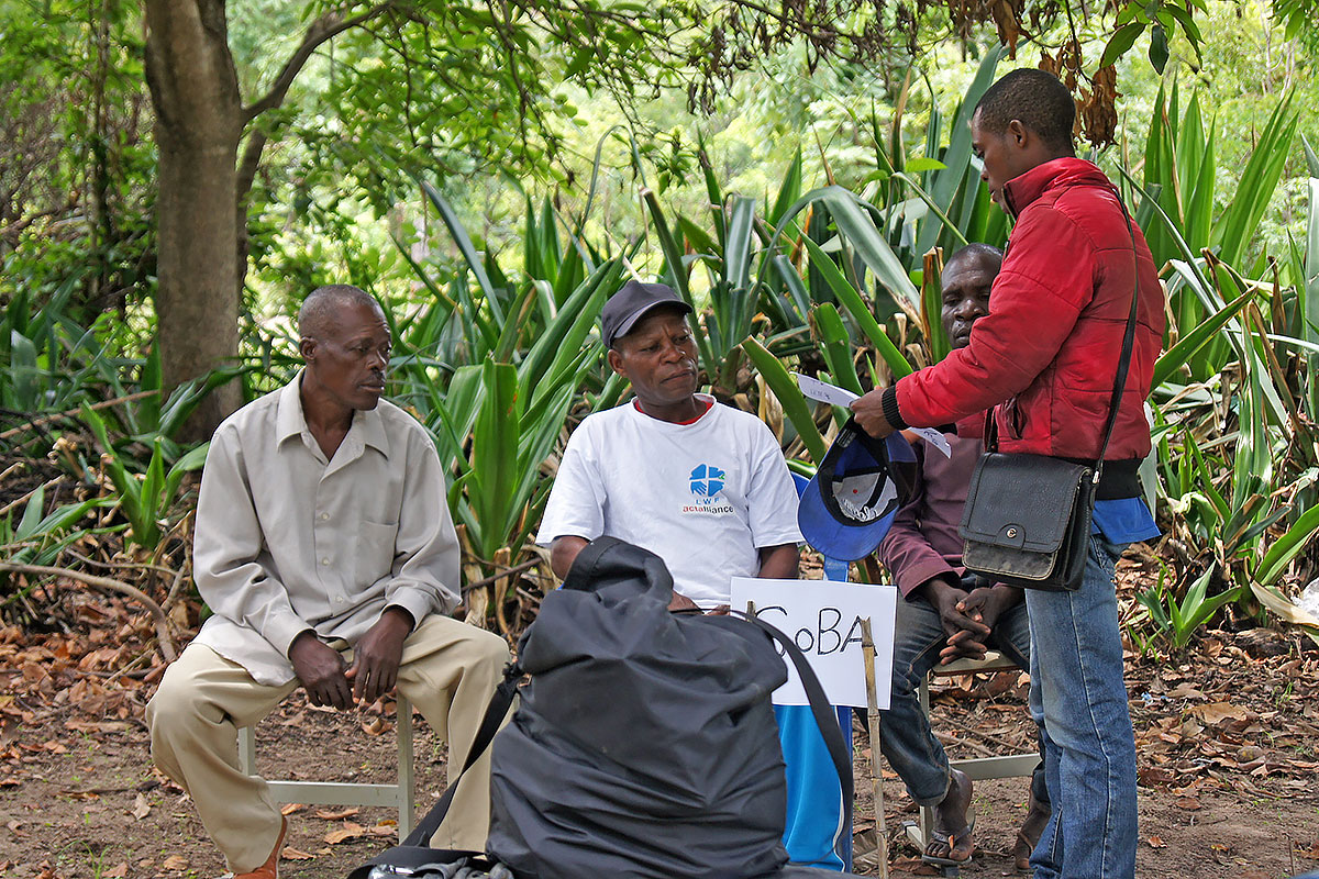 In a village play, farmers tell the story of how an investor convinced a village chief to give him land. The role of the village chief is here played by the soba himself (sitting, middle).