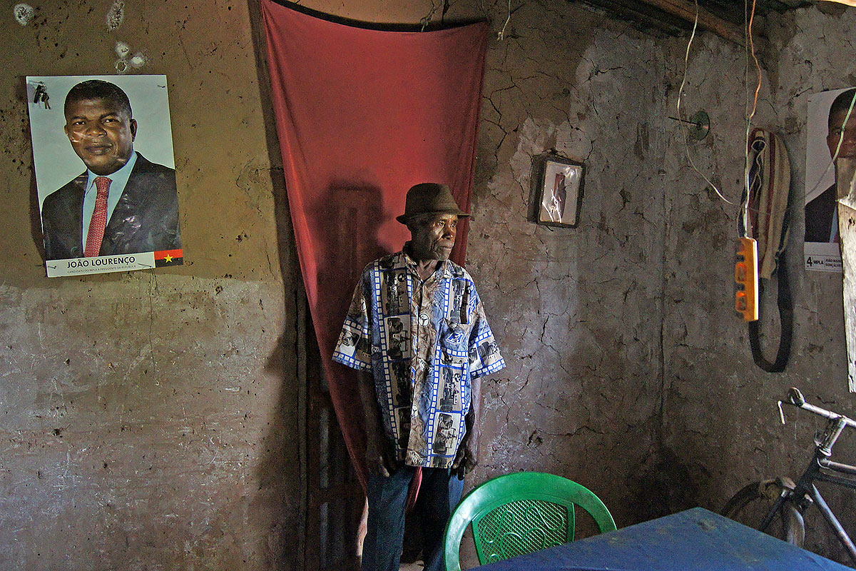 A farmer in his house in Moxico province, Angola. Like many others, he is a strong supporter of the ruling party and the president, who is depicted on the posters.