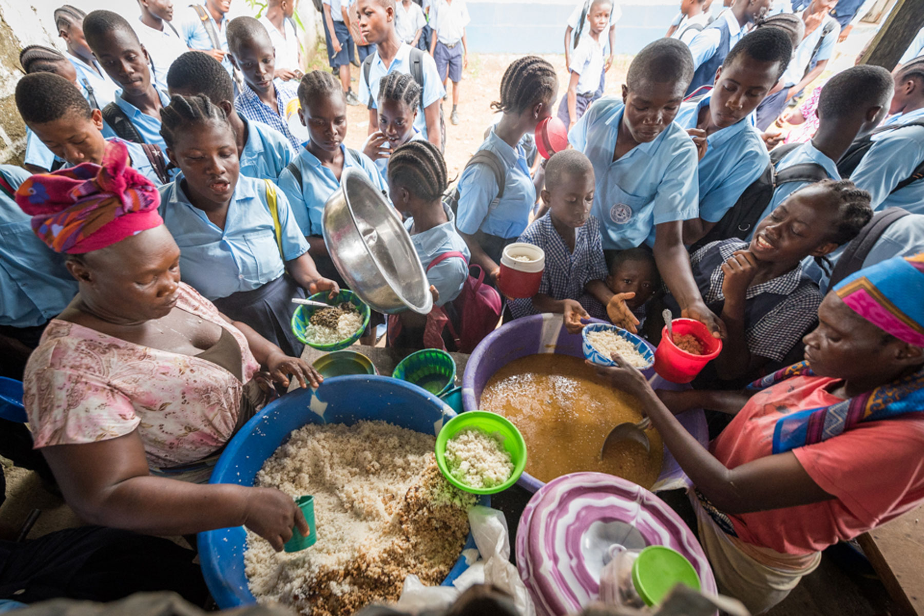 Children gather around a hot meal at Mother Tegeste Stewart.