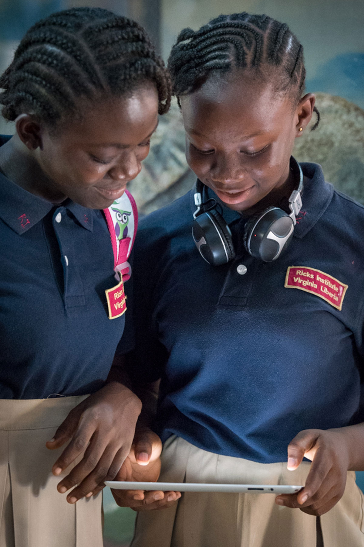 Two female students work on a tablet together during recess at Ricks Institute.