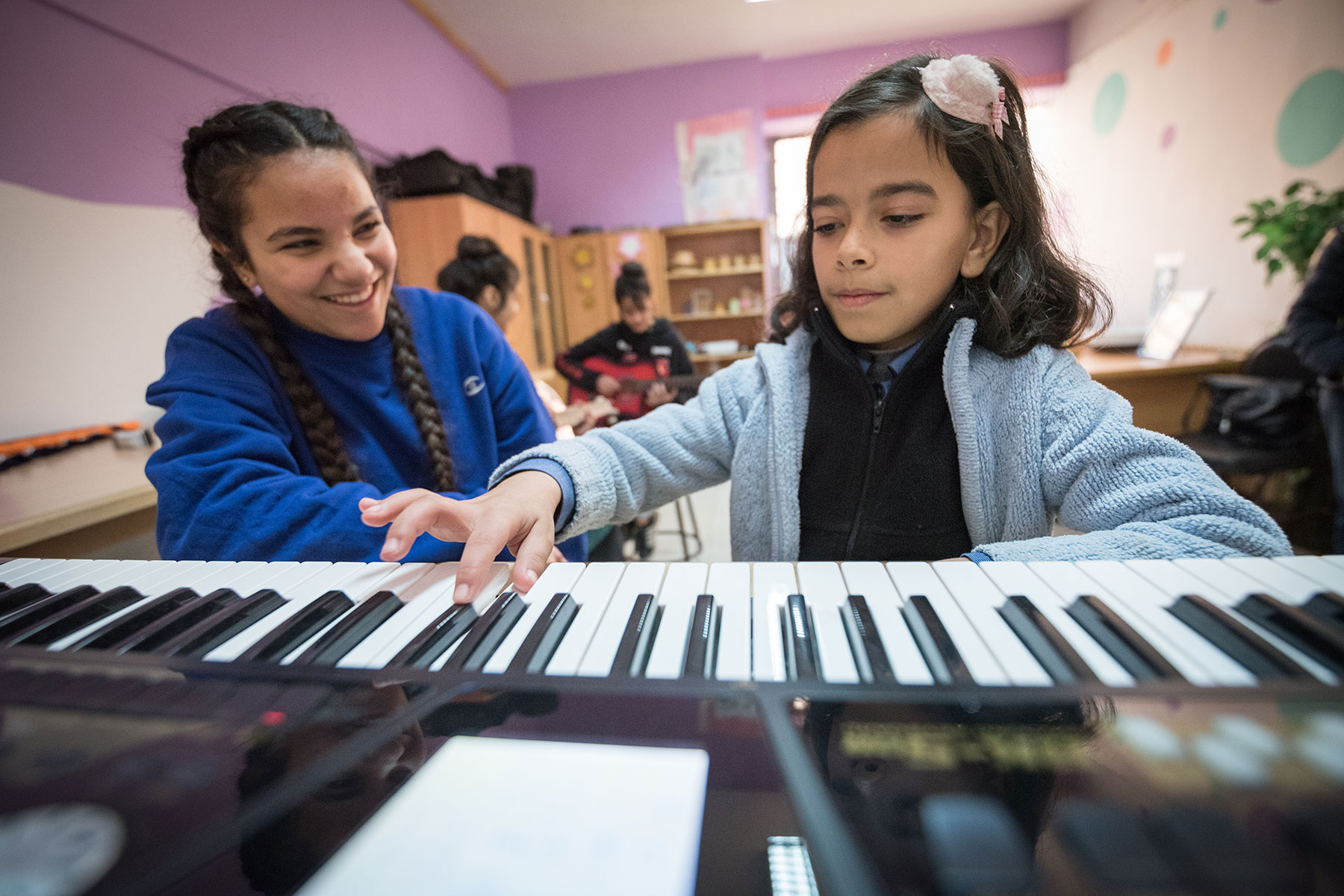 15-year-old Rena Almaharmeh (left) receives piano instructions from ten-year-old Saja (right) in the Talent Room at Rufaida Al Aslamieh Primary Mixed School.