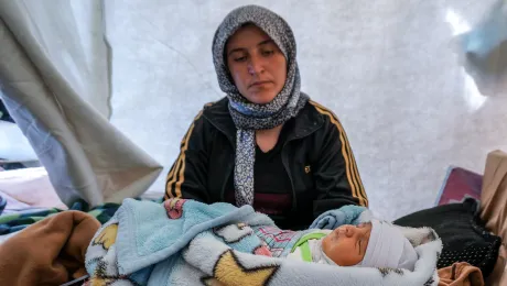 Caption: Kamla Edno and her five-day-old baby, Shahla Edno, at the Berseve 1 camp near the town of Zakho in northern Iraq in December 2014. The baby lies in a plastic crate used to store vegetables. Photo: LWF/ S. Cox