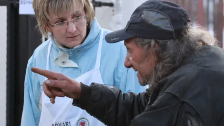 Social worker Anita VÃ¡rkonyi listens to a man in DombÃ³vÃ¡r, Hungary, where the Lutheran diaconal organization provides services, such as hot meals in winter. Photo: LWF