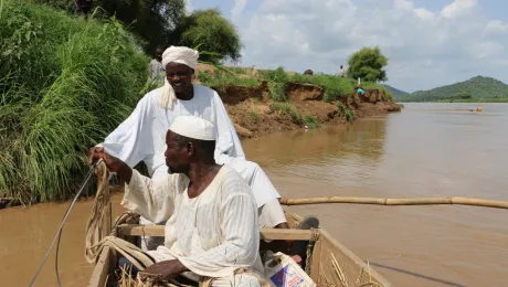 Djouma Ousmane (in the back) ferries members of the community across the river with a boat they bought with collective income from an LWF livelihoods initiative. Photo: LWF Chad