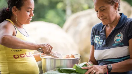 Mayerlis serves woman leader Aida a meal of sarapa â rice and chicken wrapped in a Cachibou leaf. Photo: LWF/Albin Hillert