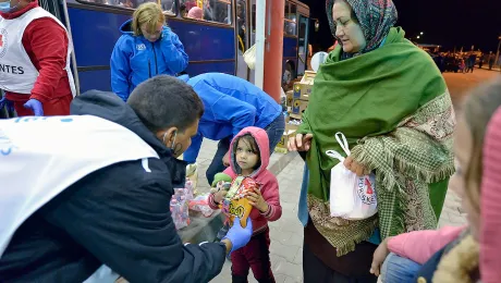 Staff from ACT Alliance member Hungarian Interchurch Aid offer food to a young refugee at Beremend, along Hungary's border with Croatia. Hundreds of thousands of refugees and migrants flowed through Hungary in 2015 on their way to western Europe from Syria, Iraq and other countries. Photo: Paul Jeffrey/ACT