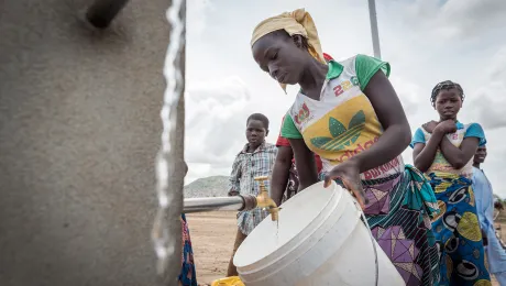 For the most vulnerable people access to sufficient and clean water is essential at times of climate change as well as during the Coronavirus disease (COVID-19) pandemic. In Minawao camp, a young woman waits for her bucket to fill up at one of the tapstands. The Minawao camp for Nigerian refugees, located in the North region of Cameroon, hosts some 58,000 refugees from North East Nigeria. The refugees are supported by the Lutheran World Federation, together with a range of partners. Photo: LWF/A