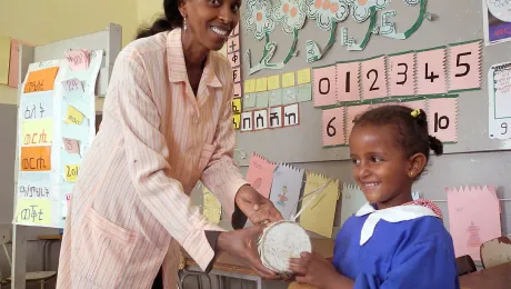 Teacher Almaz Tesfaldet shows five-year-old Luz how to play a traditional drum at the Lutheran church-run pre-school in Asmara. The Eritrean Lutheran church kindergartens in the capital and three remote villages provide learning and recreation space for children from many faith backgrounds. Photo: LWF/Rainer Lang