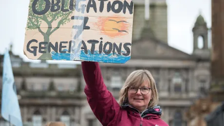 Kathrin Hall holds a sign at an interfaith vigil held at George Square on the opening day of COP26 in Glasgow, Scotland. Photo: LWF/Albin Hillert