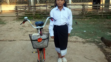 Chanset with her uniform and bicycle in front of her school. Photo: LWF/P. Simayvanh