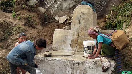 Karmu Tamang from Thangdur, Rasuwa washes bed  sheet of her six months-old baby in the public tap in Thangdur village in Yarsha 6 . LWF Nepal and BATAS foundation Nepal have rehabilitated the water scheme. Photo: LWF/ U. Pokharel