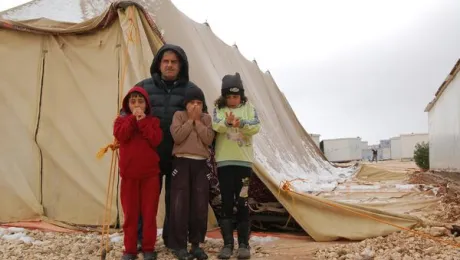 A street leader with his children in front of a half collapsed tent which is used as a Mosque. Photo: LWF/ J. Pfattner