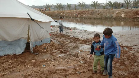 Children walk near flooding in tented settlement Jordan. Photo: Karl Schembri/Oxfam (CC-BY-NC-SA)