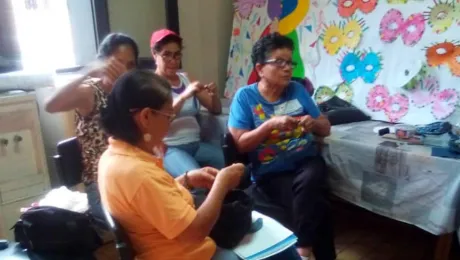 Participantes en un taller de costura para madres y miembros de la comunidad en la "Casa de la Amistad" dirigida por IELV. Todo aquí está hecho a mano, y el facilitador da instrucciones de la misma manera, ya que una máquina de coser no es asequible. Fotos: IELV/Judith Bracho Villegas.