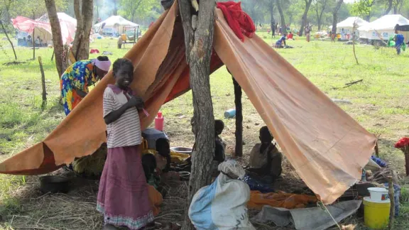 A newly-arrived family to Upper Nileâs Yusuf Batil camp settles into temporary shelter while waiting to receive a tent. Â© LWF/M. Retief