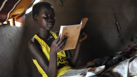 Ein junges Flüchtlingsmädchen aus dem Südsudan macht in Adjumani, Norduganda, ihre Schularbeiten. Die verbesserte Einschulungsrate von Mädchen wird bedroht durch die fehlende Versorgung mit Hygieneartikeln. Foto: LWB/M. Renaux