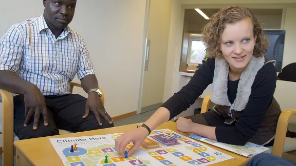 Programmreferent Lokiru Matendo Yohana (li.) und Jugendreferentin Caroline Richter (beide LWB) spielen das vom LWB konzipierte Brettspiel Climate Hero und entwickeln dabei kreative Ideen, wie der Klimawandel gestoppt werden kann. Foto: LWB/S. Cox