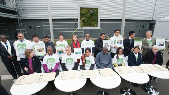 An interfaith group of religious leaders sits in front of empty trays during a public action promoting the Fast for the Climate campaign during the COP21 UN climate summit in Paris, France. Photo: LWF/R. Rodrick Beiler