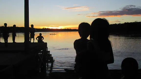 Kinder einer indigenen Gemeinschaft in Choco betrachten vom Flussufer aus den Sonnenaufgang. Foto: LWB Kolumbien