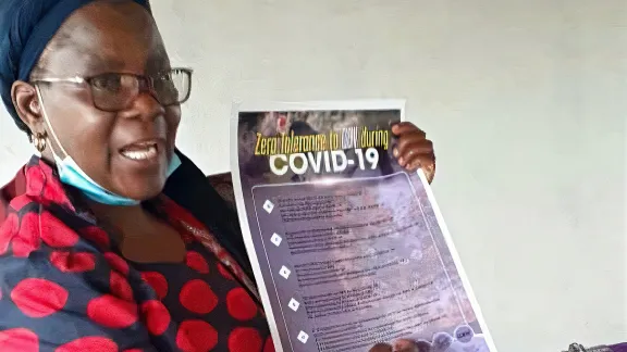 The Rev. Elitha Moyo displays a COVID-19 best practices and gender-based violence prevention poster in the Mberengwa Ward 23 area, a border community in Zimbabwe at increased risk for both. Photo: ELCZ