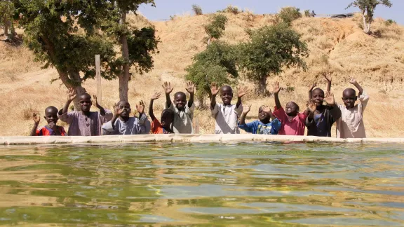 Kinder hinter einem Tank zum Filtern von Trinkwasser im Flüchtlingslager Minawao, Kamerun, im Dezember 2017. Foto: LWB/C. Kästner