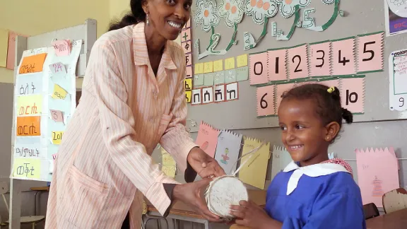 Teacher Almaz Tesfaldet shows five-year-old Luz how to play a traditional drum at the Lutheran church-run pre-school in Asmara. The Eritrean Lutheran church kindergartens in the capital and three remote villages provide learning and recreation space for children from many faith backgrounds. Photo: LWF/Rainer Lang