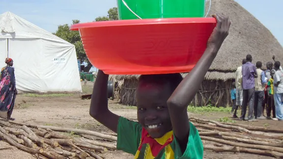 A young boy collects buckets for washing and water transport at the LWF distribution point in Leitchuor camp. Photo: LWF Ethiopia/ Heidi Lehto