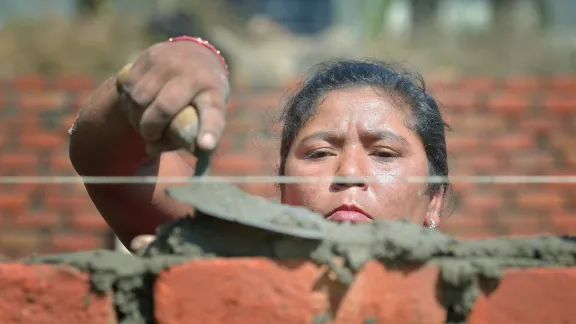 Bhagwati Tamang errichtet nach dem verheerenden Erdbeben vom April 2015 im Dorf Jogimara im Zentrum Nepals eine Mauer. Nach der Erdbeben-Katastrophe in der Tausende von Menschen Häuser und Lebensgrundlagen verloren, arbeitete der LWB gemeinsam mit Islamic Relief Worldwide und anderen Partnern daran, in abgelegenen Dörfern Unterkünfte zu errichten. Foto: Paul Jeffrey/ACT