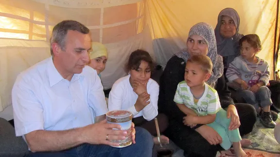 Rev. Michael Martin shares a tin of sweets with a Syrian family at the Zaâatri refugee camp. Photo: LWF Jordan/E. Gano