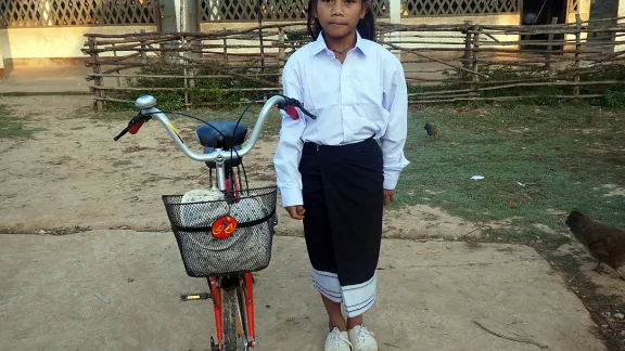 Chanset with her uniform and bicycle in front of her school. Photo: LWF/P. Simayvanh