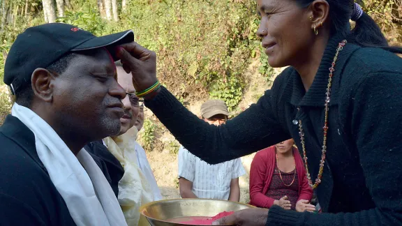 ACT-Generalsekretär John Nduna empfängt von einer Frau aus Sanogoan das Tika, ein traditionelles Stirnmal. Foto: LWB/ Lucia de Vries