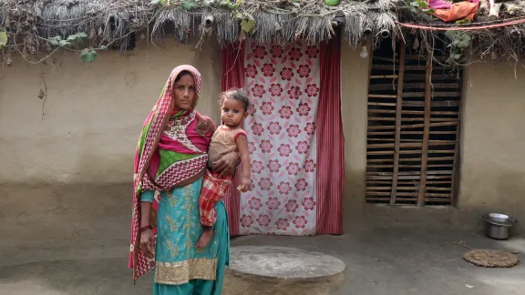 Sakina Khatun holds her youngest child in front of the family home, which needs a better roof and sanitation. All photos: LWF/ Y. Gautam