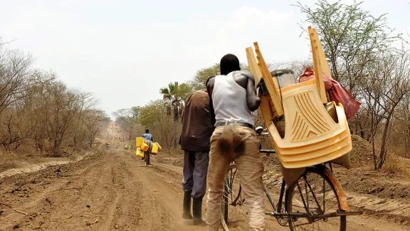 A refugee carts goods toward Uganda