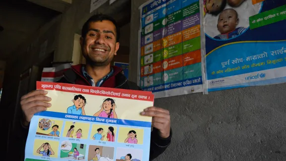 Posters, like the one held by counselor Pradeep Subedi, show the psychological impact of earthquakes on children. Photo: LWF/Lucia de Vries