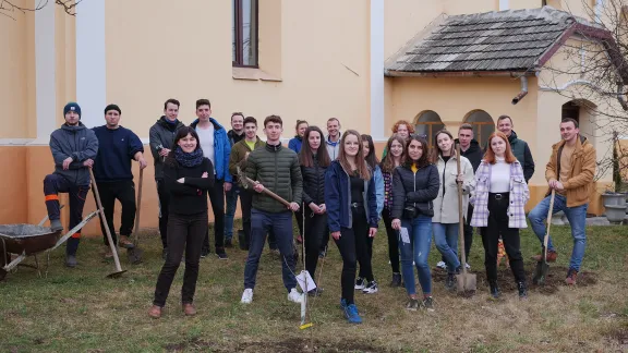 Junge Menschen von der Evangelisch-Lutherischen Kirche in Rumänien pflanzen Setzlinge im Kirchgarten der Alszeg-Kirche in Hosszúfalu. Foto: EVIKE