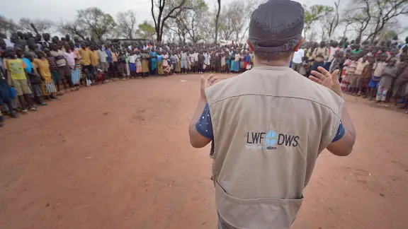 An LWF staff member speaks to children as they line up before class at a school in the Ajuong Thok refugee camp in South Sudan. Rising levels of violence this week have forced the LWF to evacuate staff from the capital. Photo: ACT/Paul Jeffrey