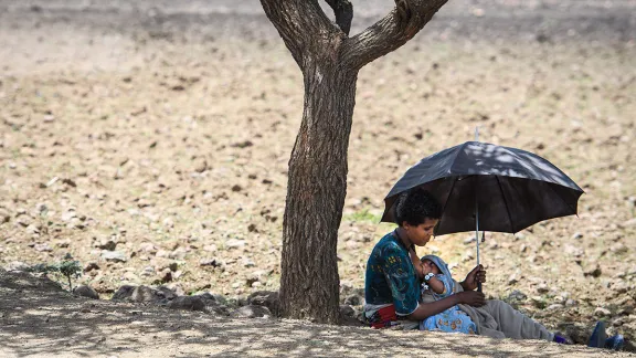 A woman nurses her child in the shade of a tree trunk in Lalibela, Ethiopia. Photo: Magnus Aronsson/ Church of Sweden