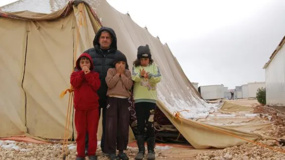 A street leader with his children in front of a half collapsed tent which is used as a Mosque. Photo: LWF/ J. Pfattner