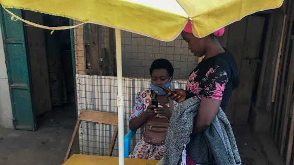 Vestina betreut eine Kundin bei ihrem Geschäft für mobiles Bezahlen in der Kyangwali-Flüchtlingssiedlung. Foto: LWB-Uganda