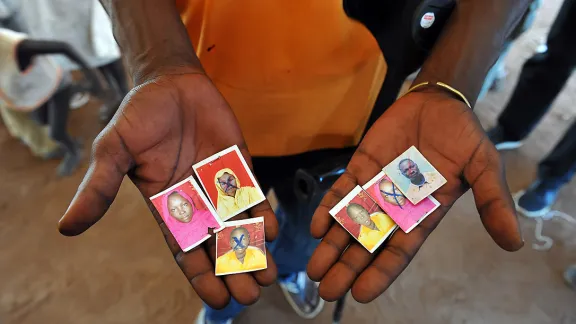 Im Aufnahmezentrum Njumanzi in Adjumani (Uganda): Ein Flüchtling zeigt Bilder von Angehörigen, die bei den Kämpfen im Südsudan ihr Leben verloren haben. Foto: LWB/M. Renaux