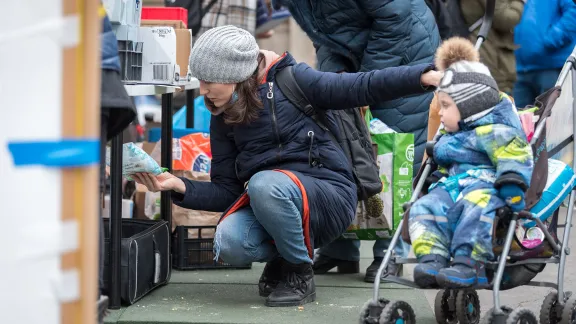 Ukrainian refugee woman Alona looks at supplies at one of the aid workersâ stands at Nyugati train station in Budapest. Alona, her 1.5-year-old son, and her mother arrived from Ukraine on 6 March, following a 26-hour long journey from the capital city Kyiv. All photos: LWF/Albin Hillert