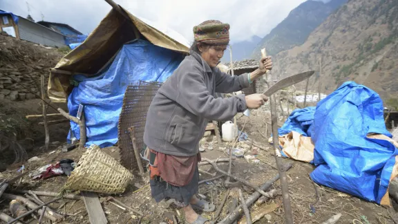 An elderly woman in Gatlang village, Rasuwa district, at the border with Tibet, uses untreated timber to rebuild her home. LWF helps people to rebuild their village the traditional way. Photo: ACT/Paul Jeffrey