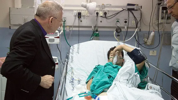 Bishop Munib Younan speaks to an injured boy in the Intensive Care Unit of St. Joseph's Hospital. Photo: D. Hudson/ELCJHL