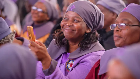 A woman films the ecumenical service while LWF General Secretary Rev. Dr Martin Junge delivers a sermon. Photo: LWF/A. Danielsson