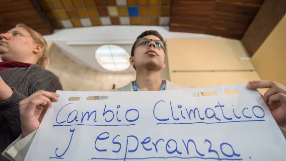 "Cambio Climático y Esperanza" (Climate Change and Hope): LWF delegate Sebastian Ignacio Muñoz Oyarzo from the Evangelical Lutheran Church in Chile holds a sheet of paper presenting a key discussion point from a gathering of faith representatives at an interfaith dialogue and prayer service on the eve of the United Nations Climate Change Conference (COP25) in Madrid, Spain. Photo: LWF/Albin Hillert