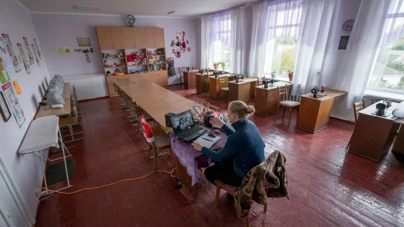 Teacher Natalia Koval leads an online class in textile handiwork at the Ichnya school of Vasilchenko in the Ichnya municipality of Chernihiv Oblast, Ukraine. The school is currently empty of its students, with classes taught online only until secure bomb shelters can be restored at the school. All photos: LWF/Albin Hillert