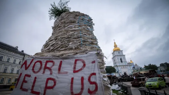 9. Oktober 2022, Kiew, Ukraine: „Welt, hilf uns“ steht auf einem Schild vor dem Kloster mit der goldenen Kuppel des Heiligen Michael im Zentrum von Kiew. Foto: LWB/Albin Hillert