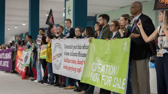 LWF delegates alongside Anglican Archbishop Julio Murray from Panama (right) and representatives from ACT Alliance (left) join 'a human chain' as part of a Global Day of Action outside the main plenary halls of COP29. Photo: LWF/Albin Hillert