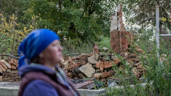 Eine ukrainische Mutter steht neben den Überresten ihres Hauses im Dorf Bil'machivka, nördlich von Ichnya im Oblast Chernihiv, nachdem es im Frühjahr 2022 von russischen Streitkräften zerstört wurde. Foto: LWB/A. Hillert